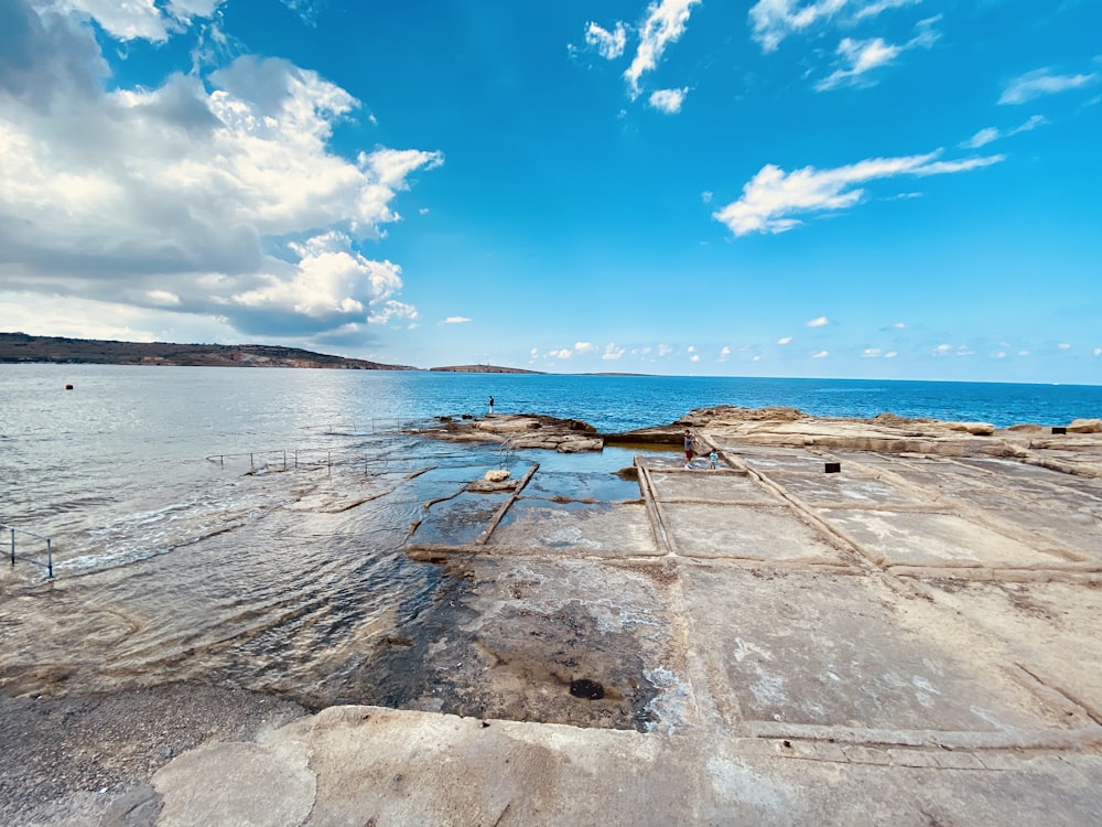 brown wooden dock on sea under blue sky during daytime