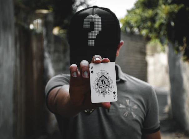 A hand holding the Ace of Swords card with a blurred forest scene in the background, evoking mystery.