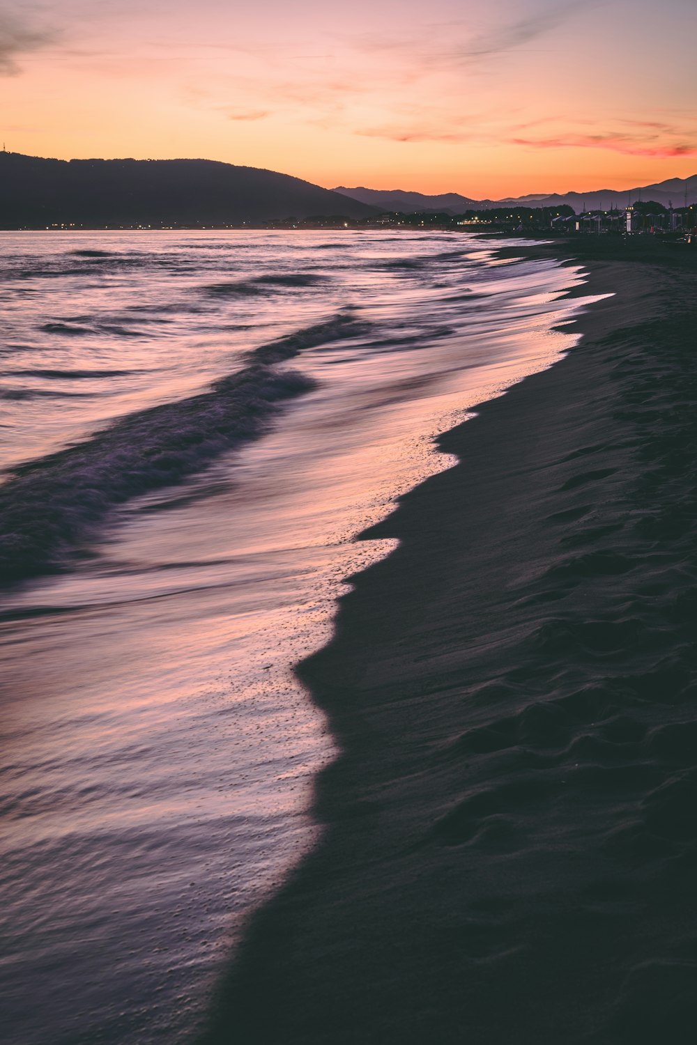 ocean waves crashing on shore during sunset