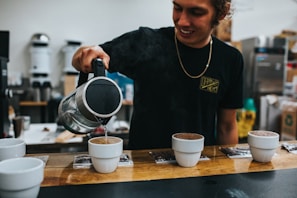 A happy customer pouring hot water from a Laundry Love Cincinnati kettle into a favorite mug.