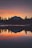 A serene mountain landscape with a calm lake reflecting the sky at sunset.
