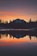 A serene mountain landscape with a calm lake reflecting the sky at sunset.