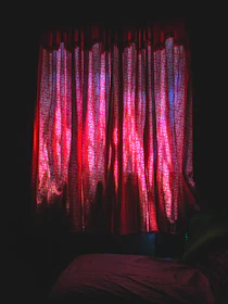 Luxurious room bathed in deep red light with shadows dancing on textured walls.