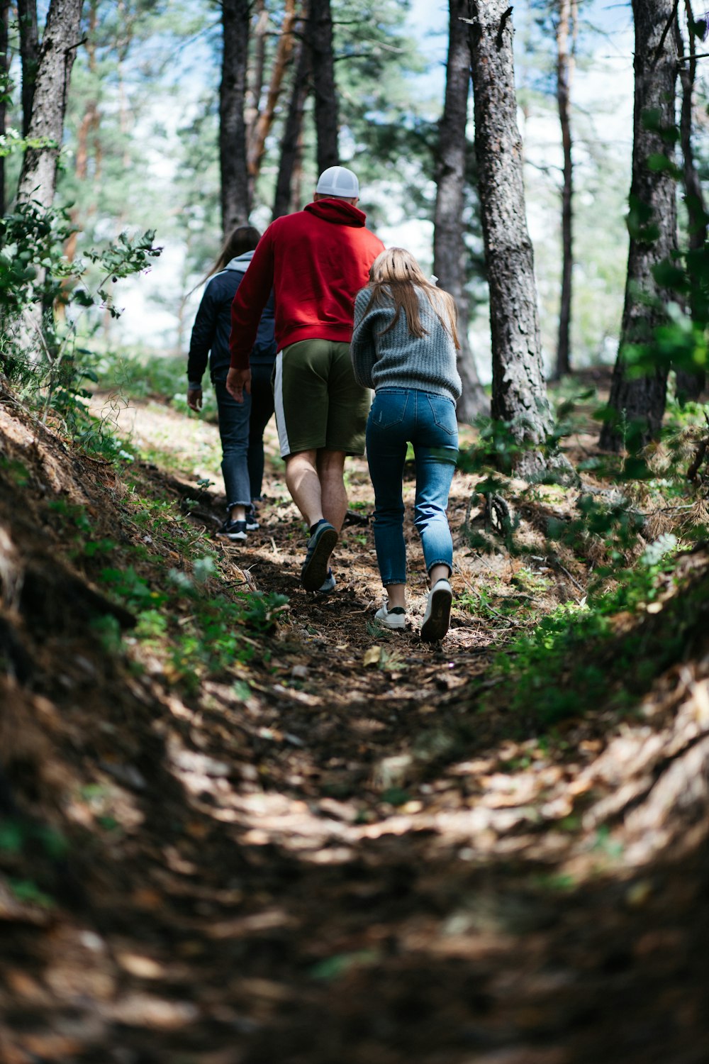 woman in brown jacket walking on pathway between trees during daytime