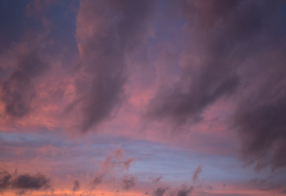 a plane flying in the sky with a sunset in the background