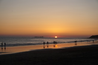 A tranquil beach at sunset with a small group practicing tai chi.