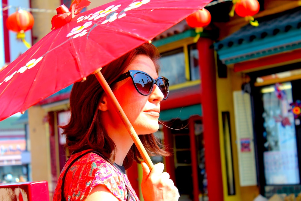 woman in red and white floral shirt holding umbrella