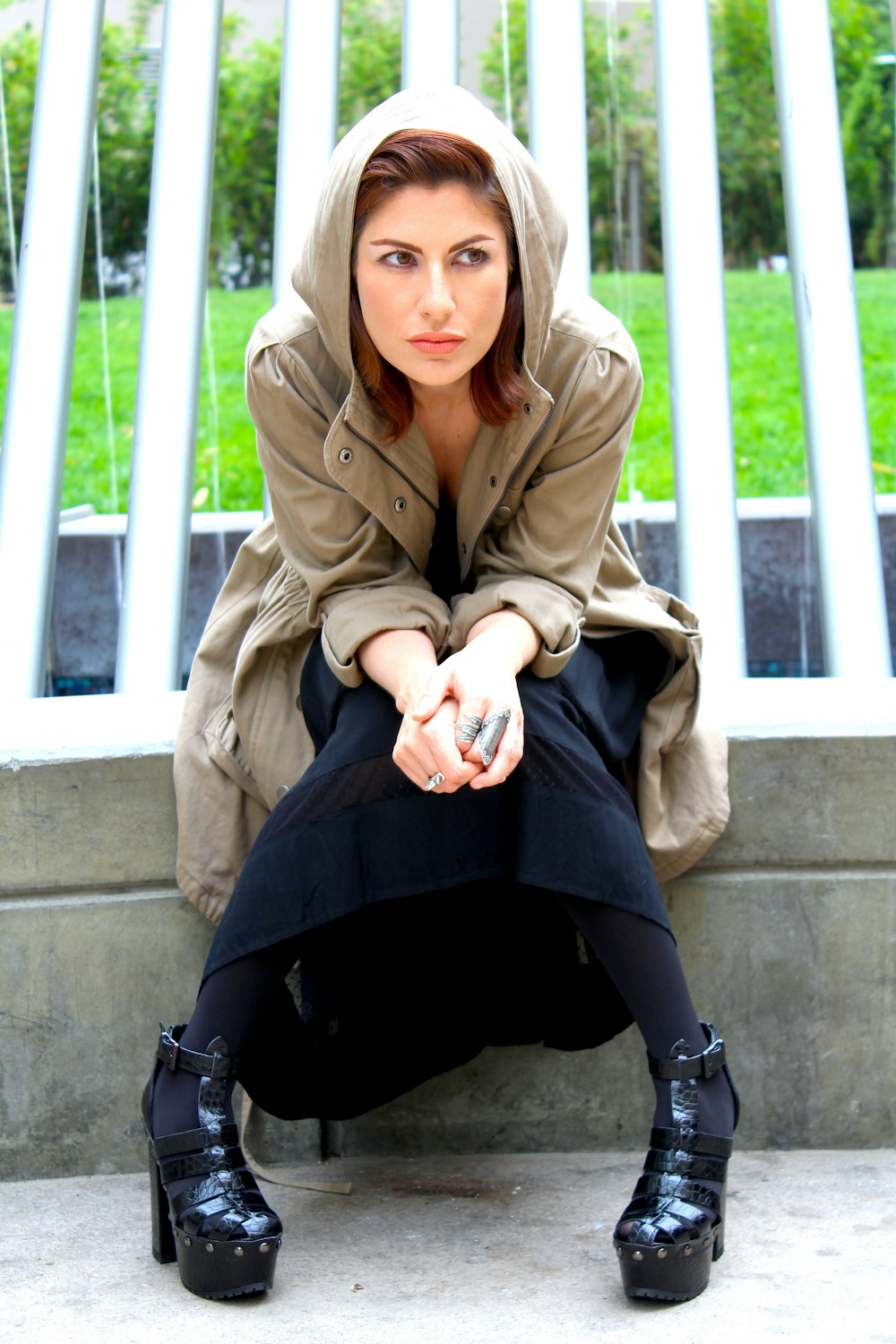 woman in brown coat and black skirt sitting on concrete bench