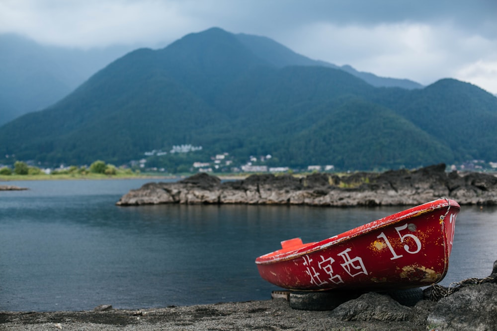 red kayak on gray sand near body of water during daytime