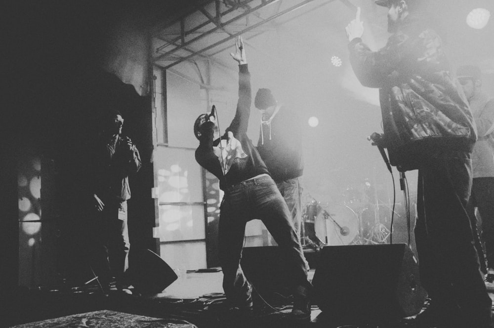 man in black jacket and denim jeans singing on stage