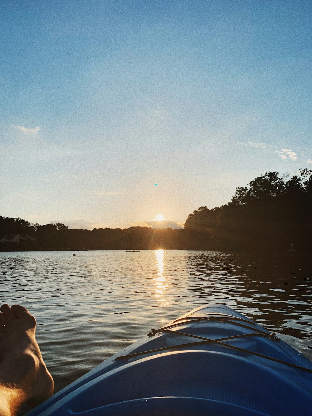 person in blue and white kayak on lake during sunset