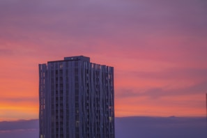 A completed landmark building against a sunset backdrop.