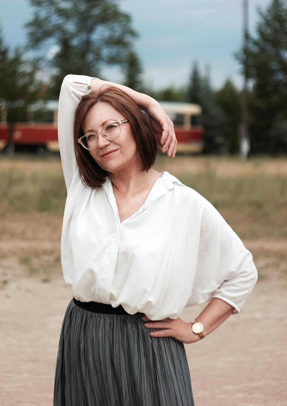 woman in white button up shirt and blue skirt standing on brown sand during daytime