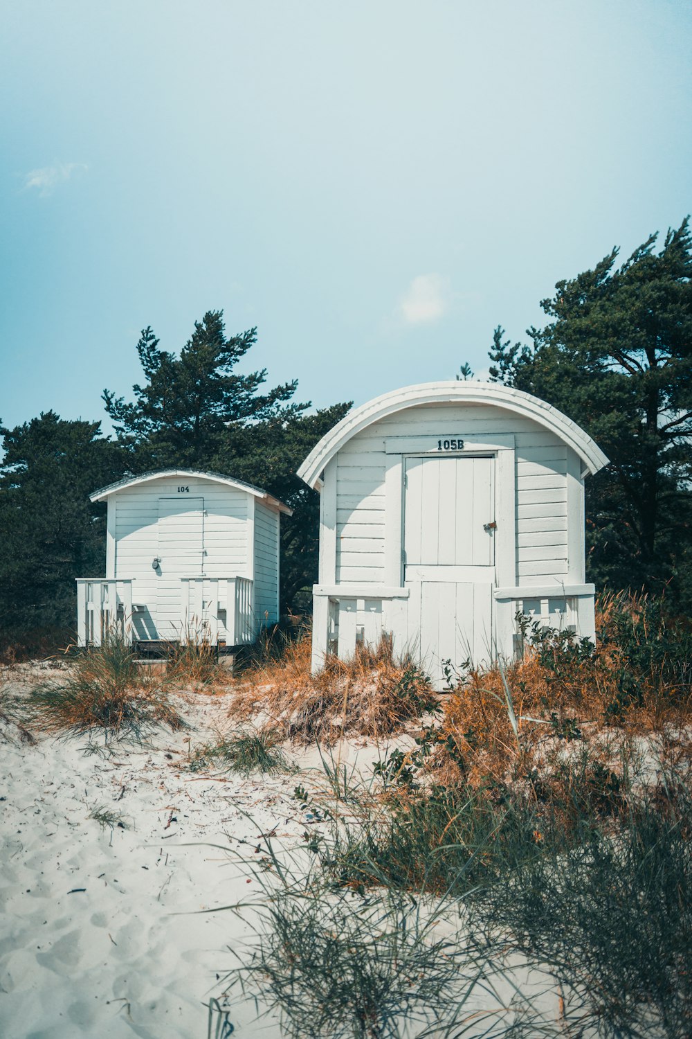 white wooden house near green trees under white clouds during daytime