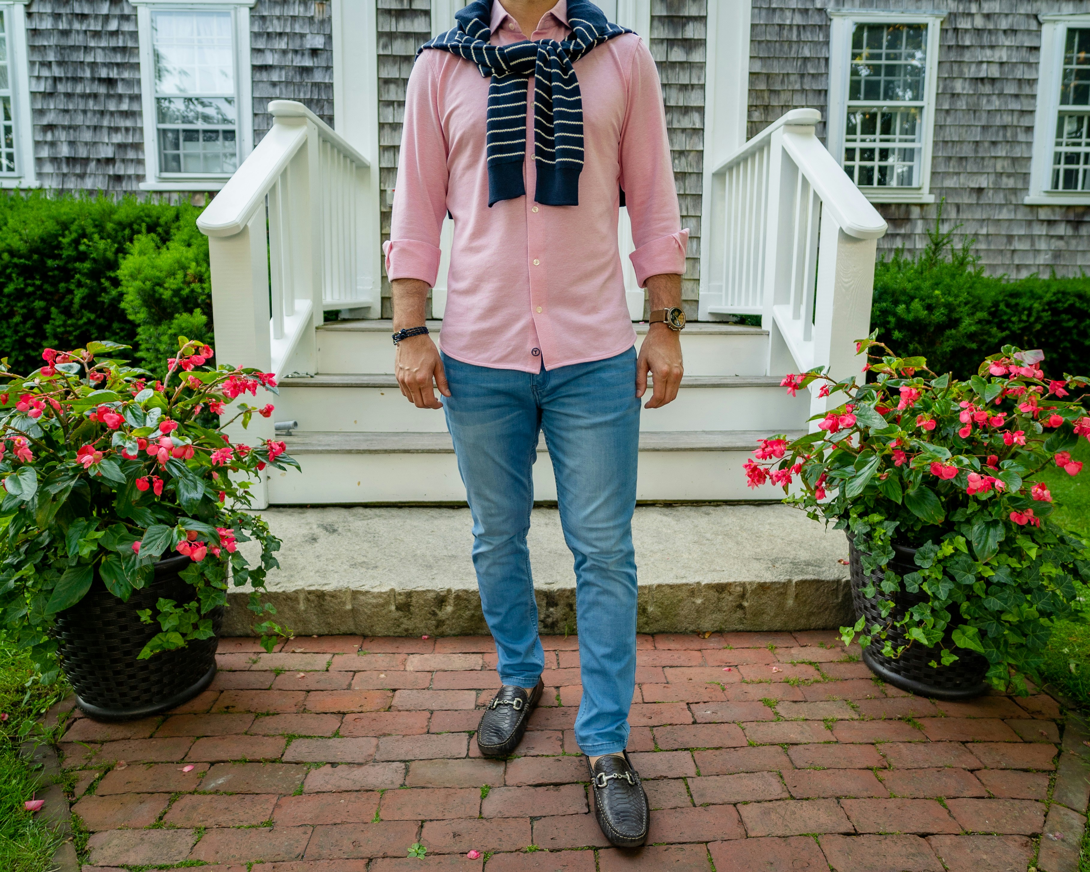 man in white dress shirt and blue denim jeans standing on brown concrete stairs