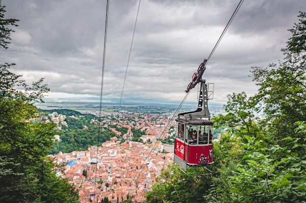 red cable car over city buildings during daytime