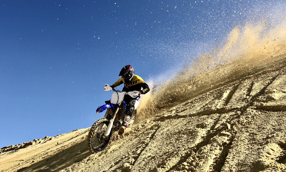 man riding motocross dirt bike on brown sand during daytime