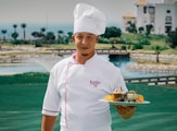 woman in white chef uniform holding green plate with food