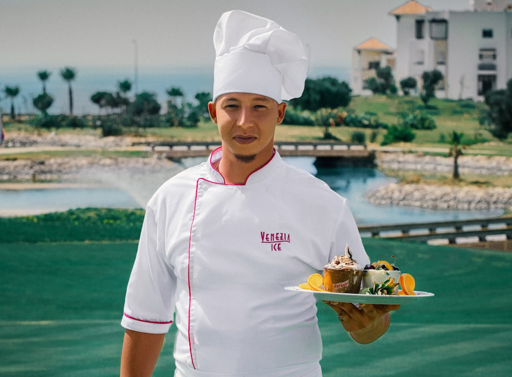 woman in white chef uniform holding green plate with food