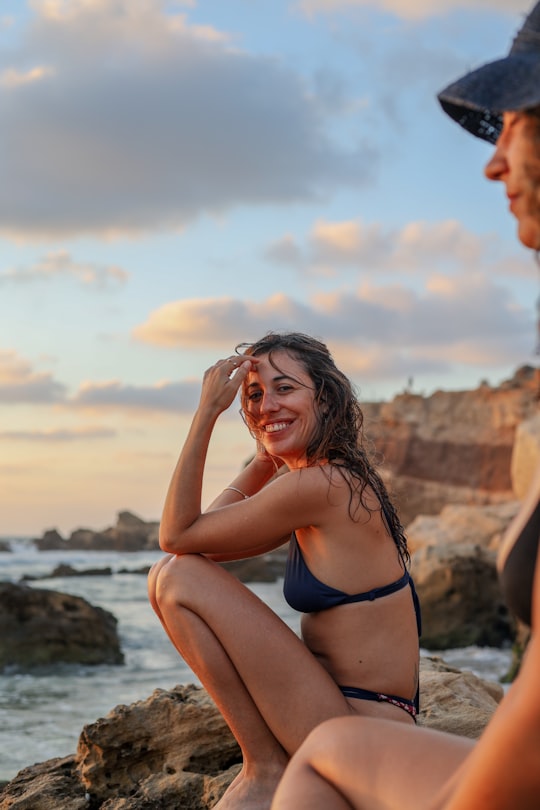 woman in blue bikini sitting on rock during daytime in Michmoret Israel