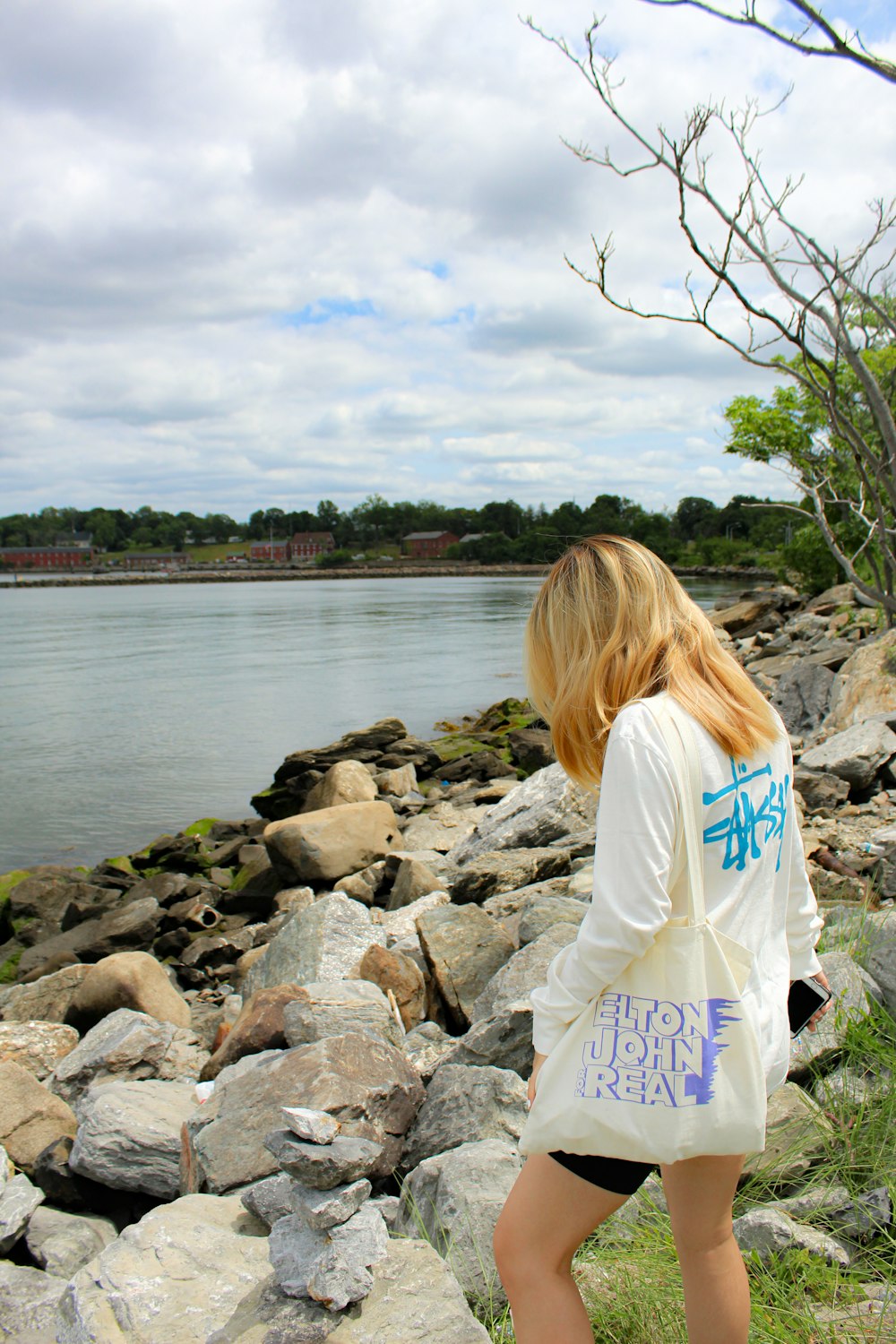 woman in white shirt sitting on rocky shore during daytime