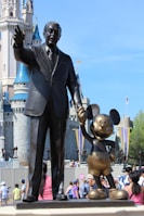 man in black suit standing beside man statue during daytime