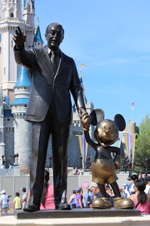 man in black suit standing beside man statue during daytime