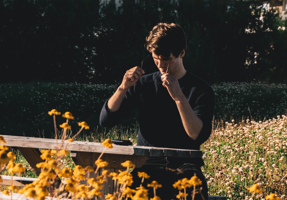 man in black t-shirt sitting on green grass field during daytime