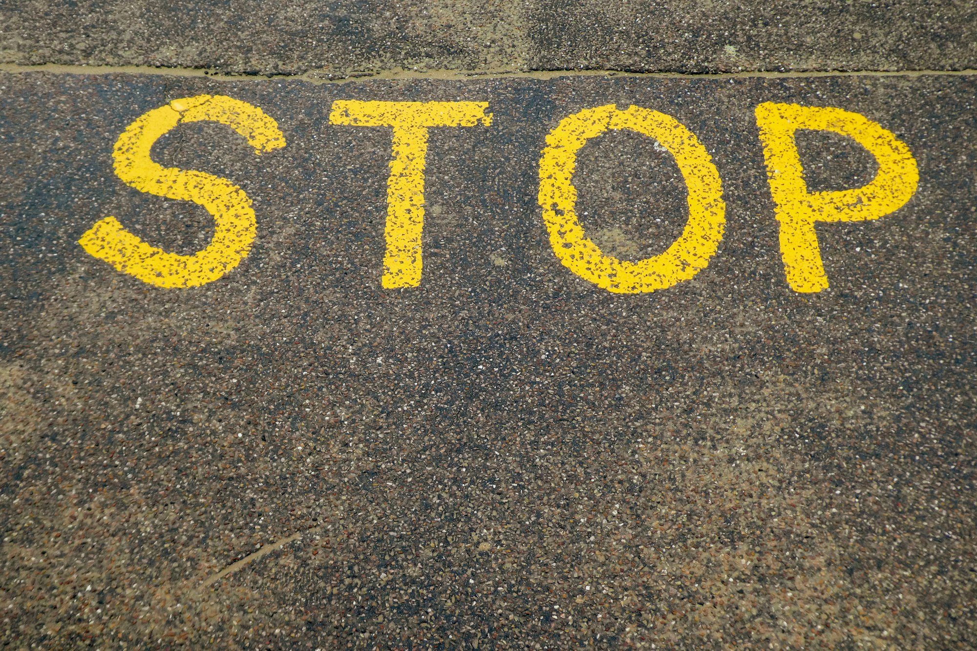 black and yellow stop print on gray concrete floor