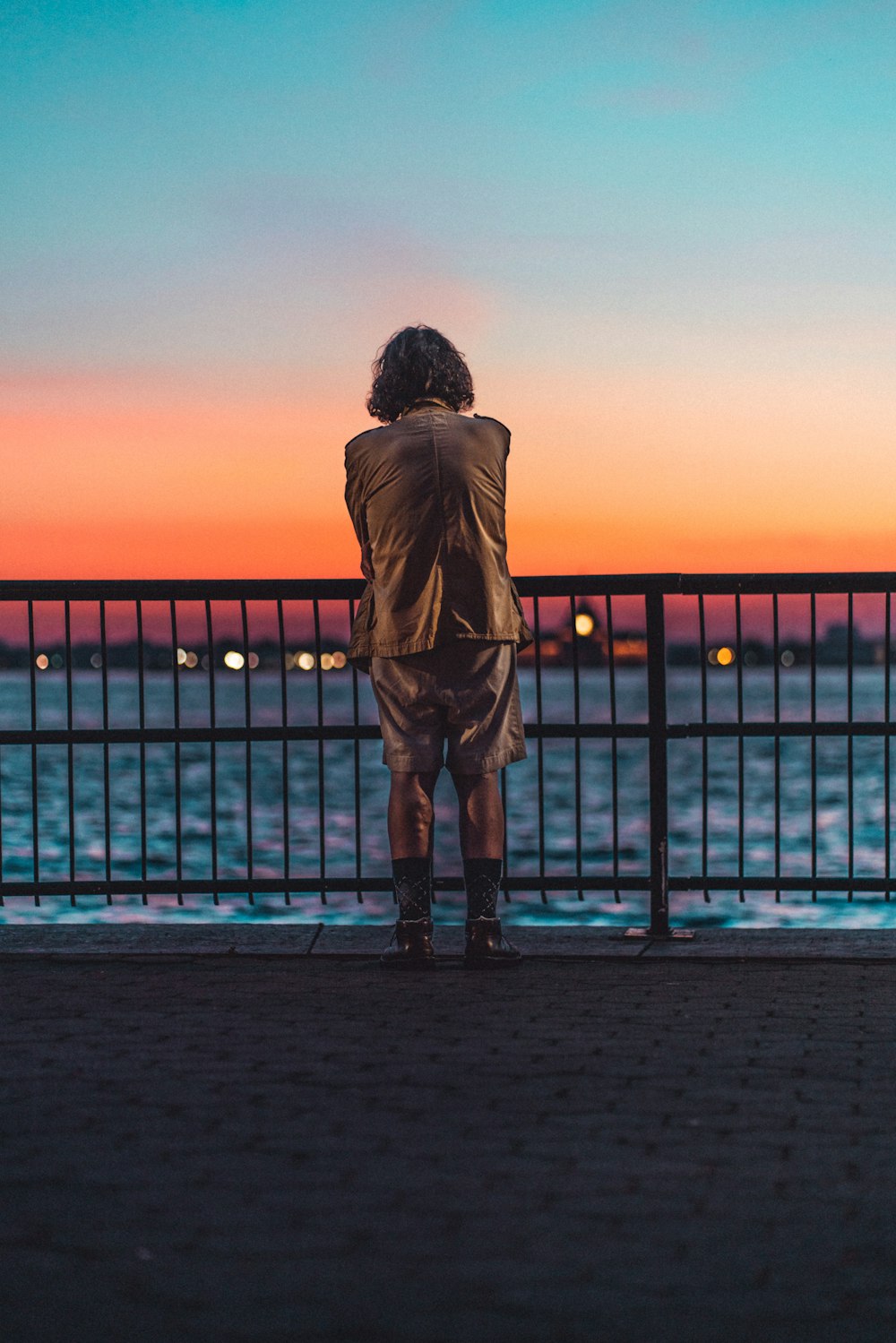 silhouette of person standing on dock during sunset