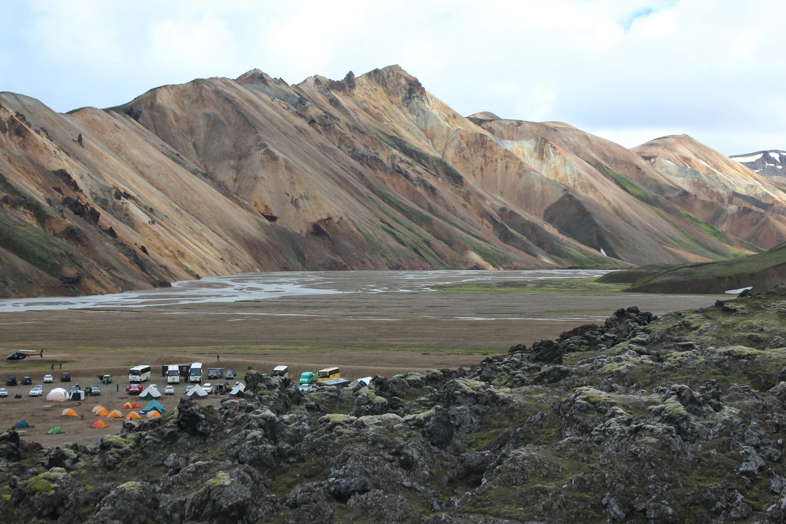 Cars parked below an Icelandic mountain