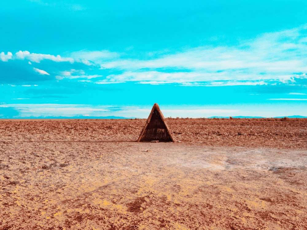 brown pyramid on brown sand under blue sky during daytime
