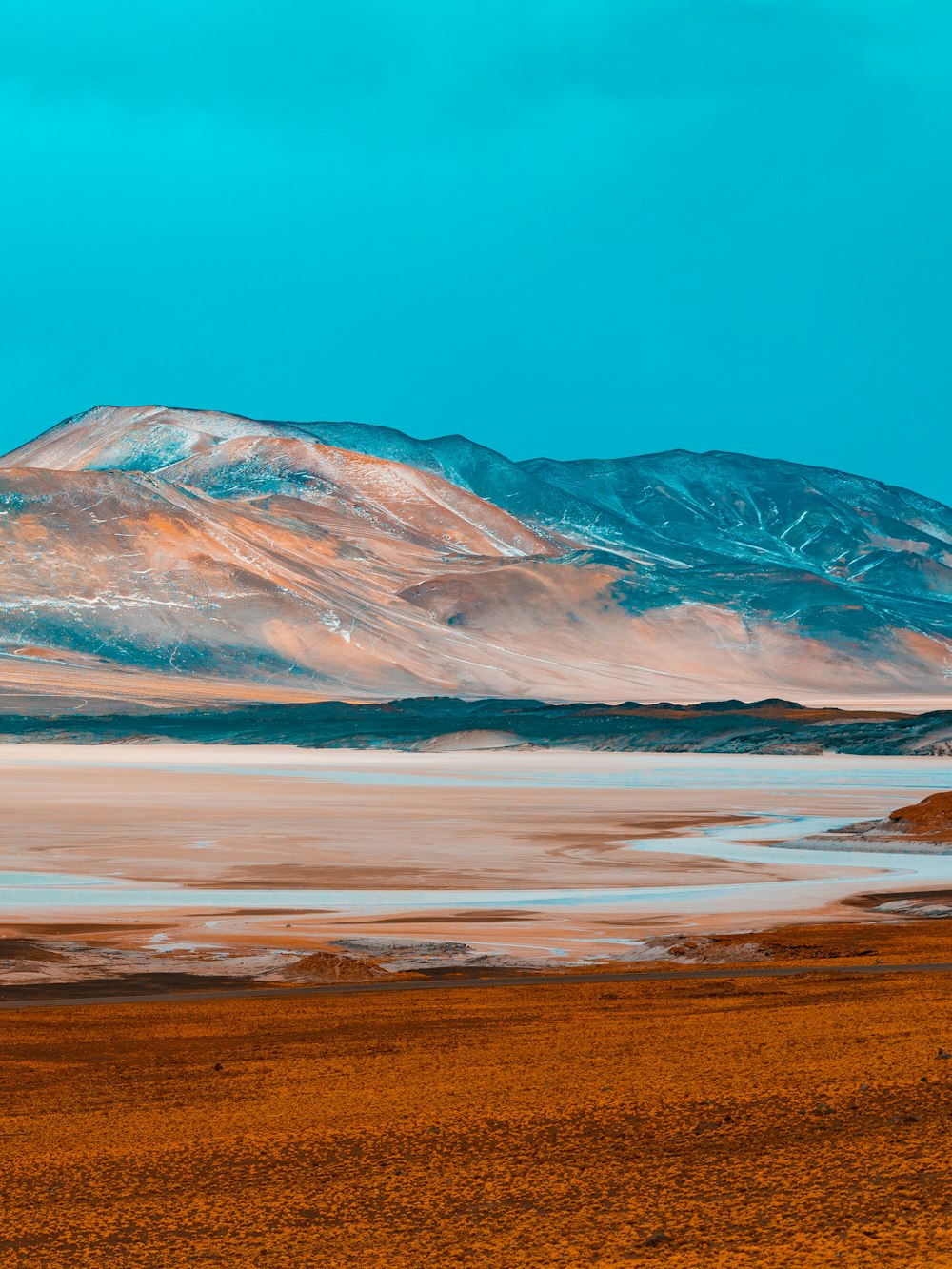 brown and white mountain near body of water during daytime