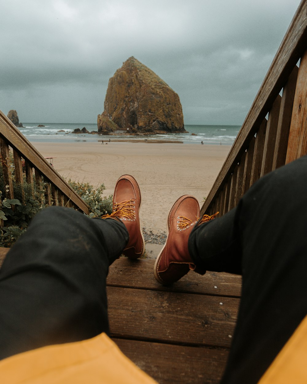 person in black pants and brown leather shoes sitting on brown wooden stairs