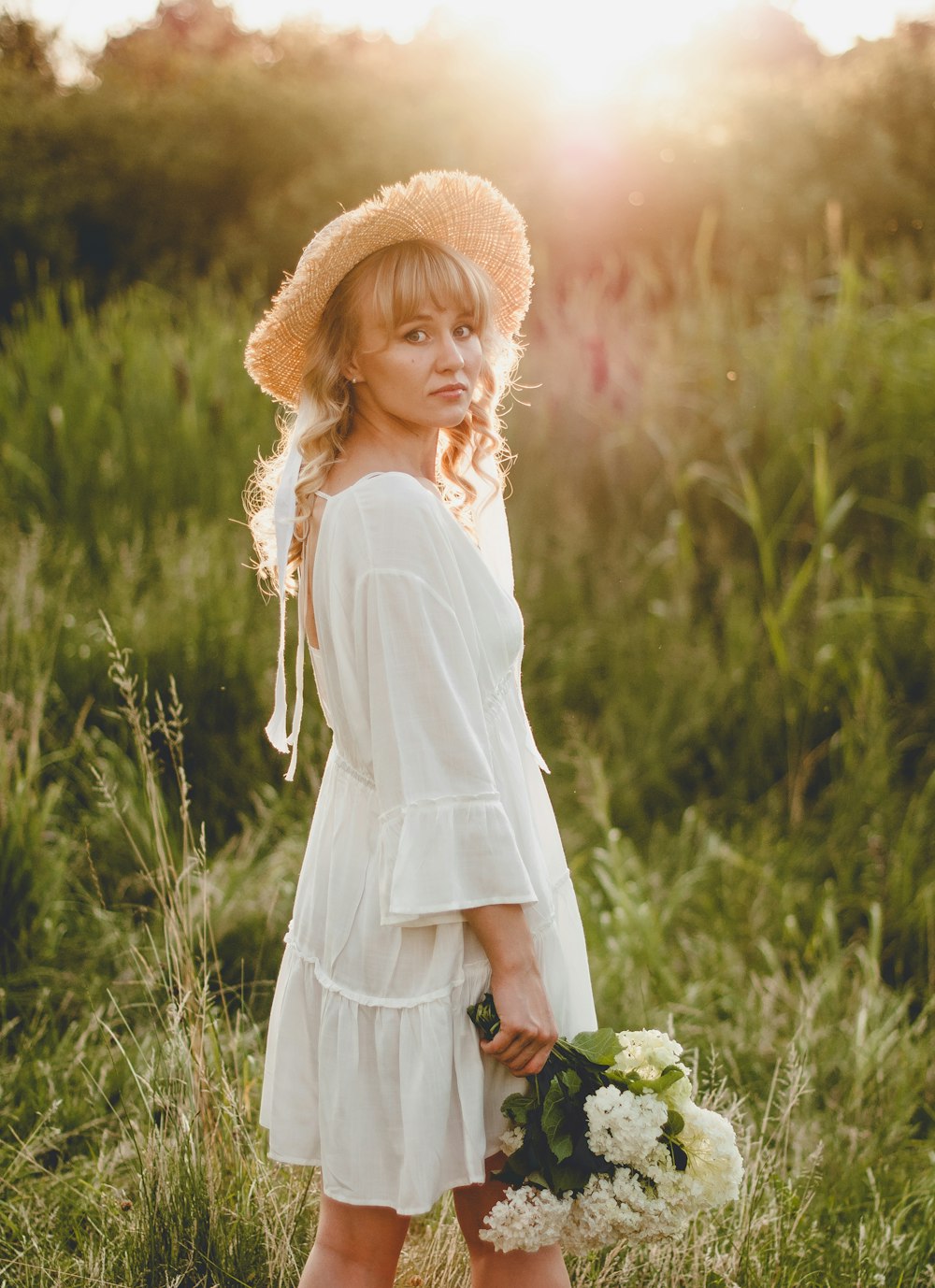 woman in white long sleeve dress standing on green grass field during daytime