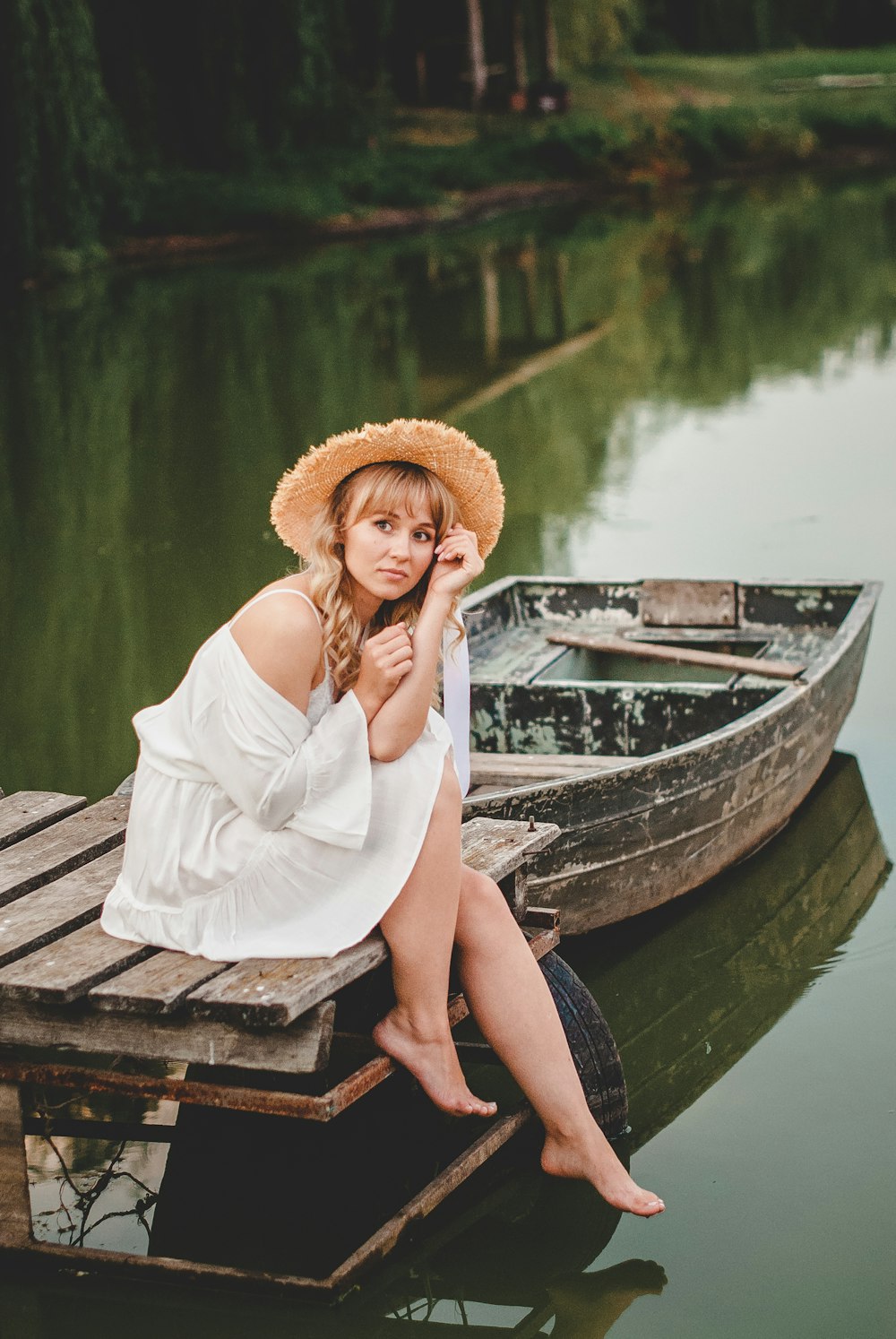 woman in white long sleeve shirt sitting on brown wooden boat on lake during daytime