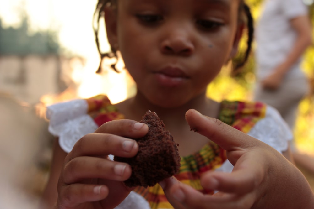 girl in white shirt holding brown stone