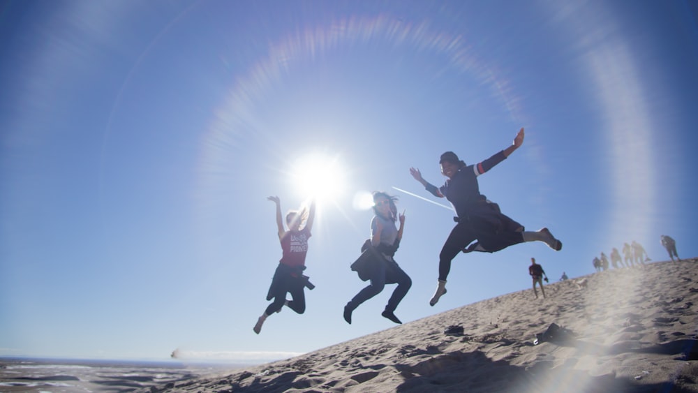 2 men jumping on brown rock during daytime