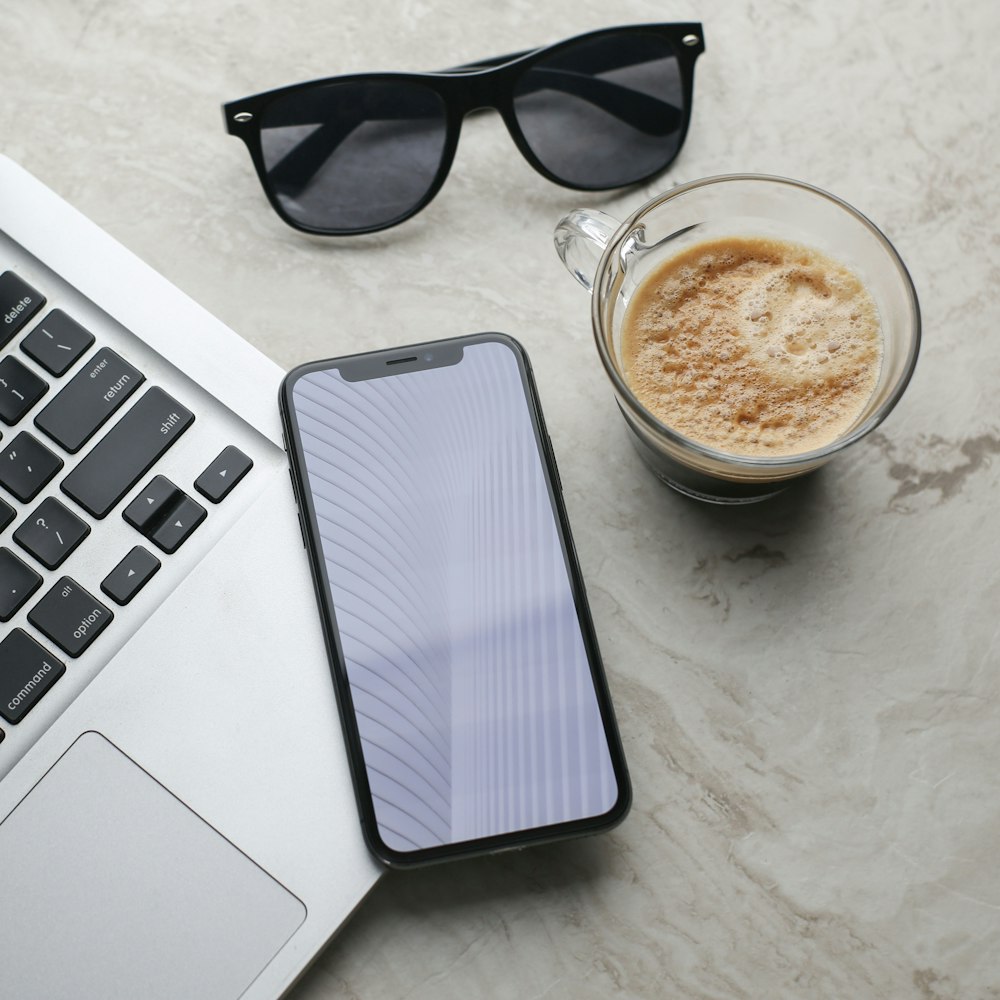 black sunglasses beside white ceramic mug on white table