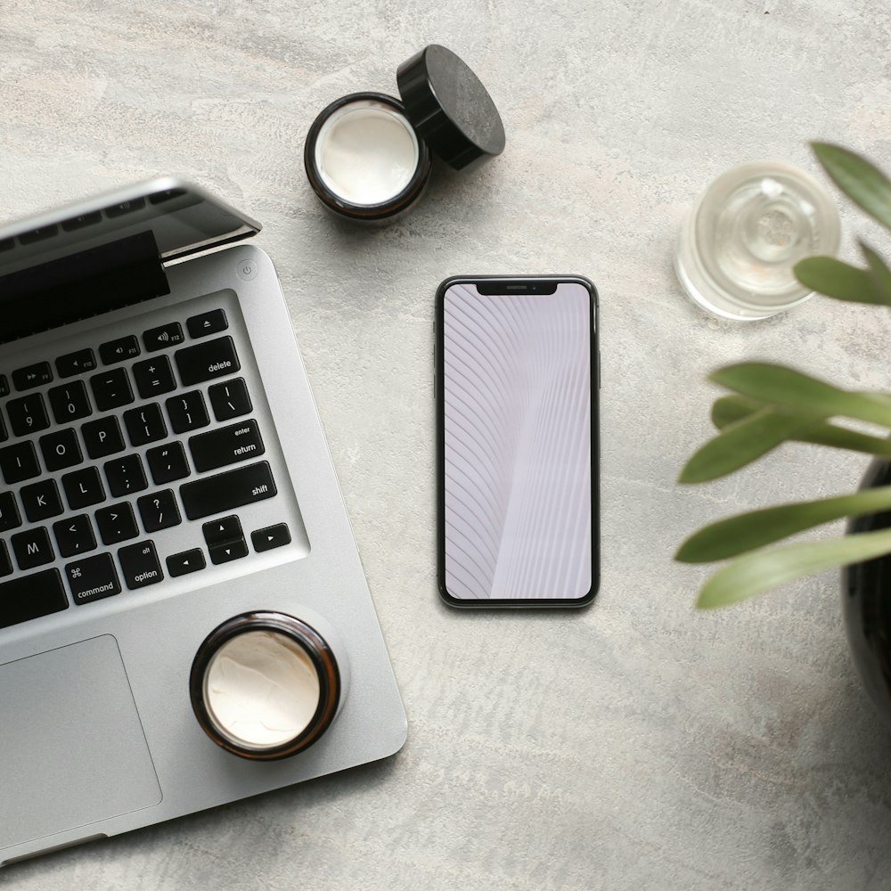 macbook pro beside white ceramic mug