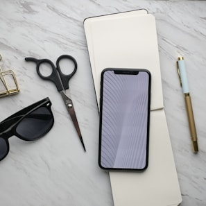 Flat lay of accessories including a leather handbag, silk scarf, and statement sunglasses on a marble surface