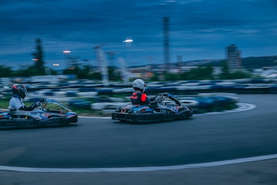 Two go-karts racing side by side with dust kicking up on the track.