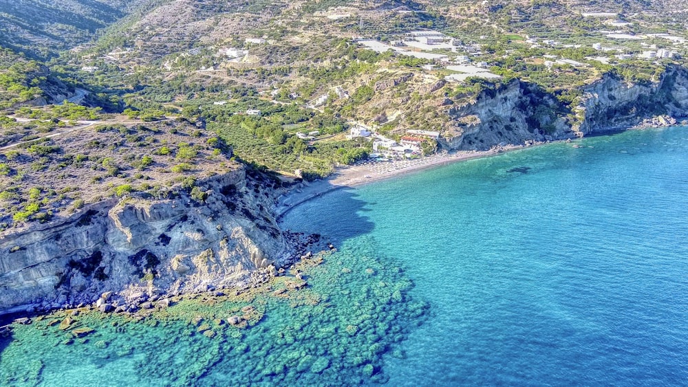 Vista aérea de la montaña verde y gris junto al mar azul durante el día