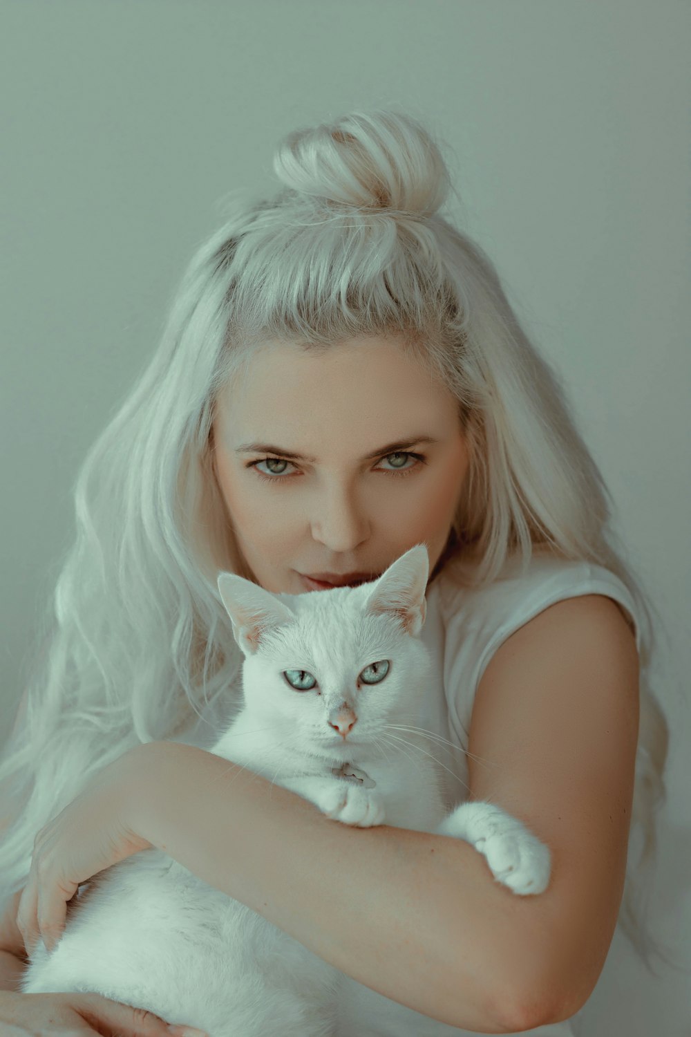 donna in canotta bianca con gatto bianco in grembo