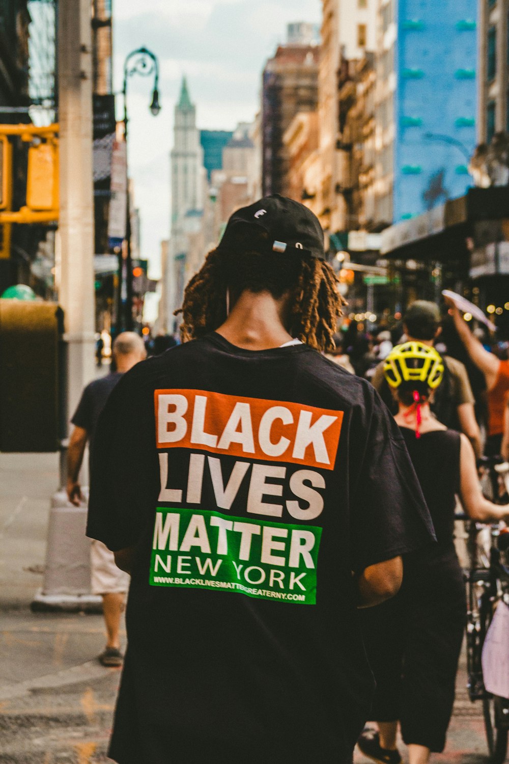 man in black and orange crew neck t-shirt standing on street during daytime