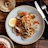 Customer smiling while enjoying a plate of seafood pasta under soft warm lights.