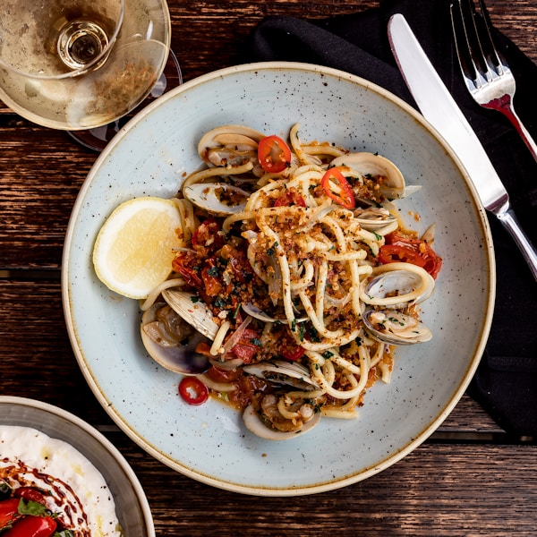 Spicy seafood pasta on a dinner table with wine.by Clark Douglas