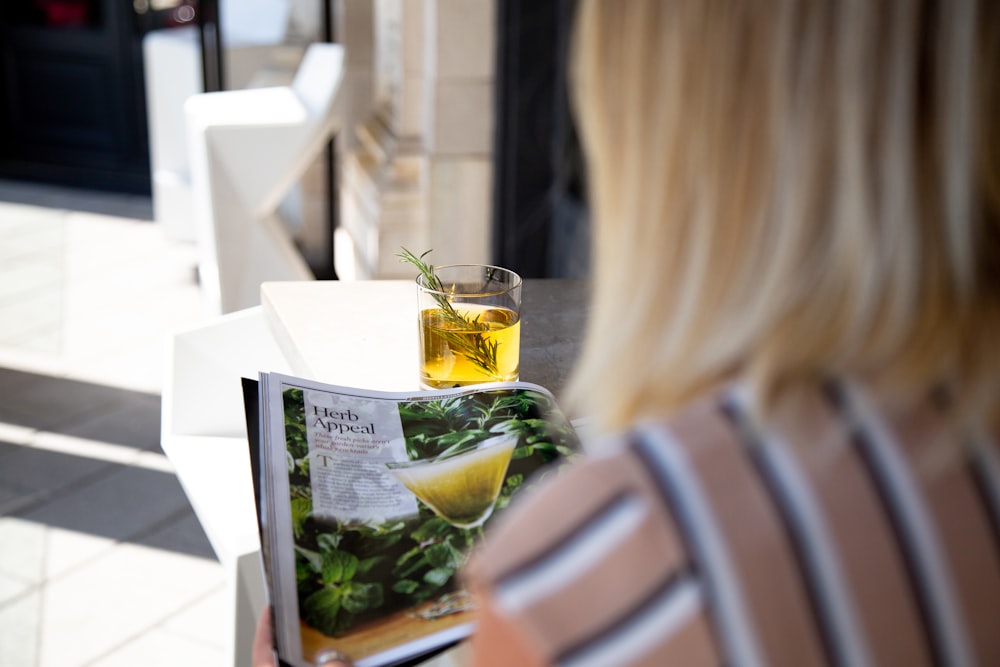 clear drinking glass with yellow liquid on white paper