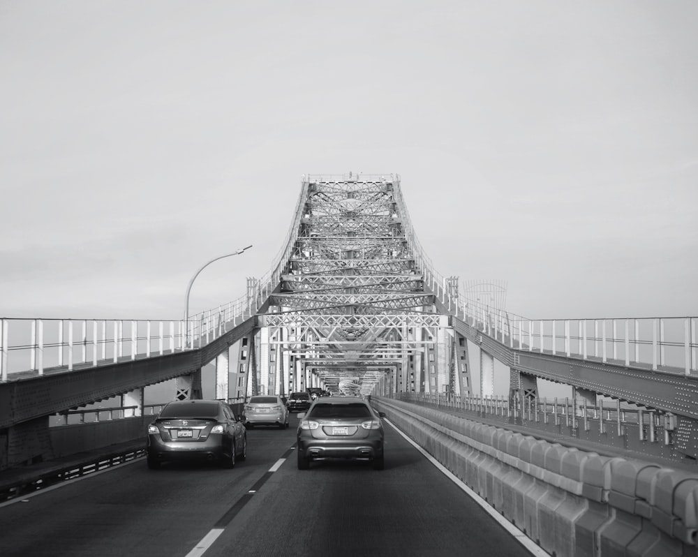 a black and white photo of cars driving on a bridge