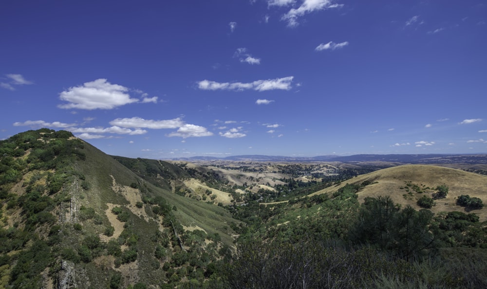 green grass field and mountains under blue sky during daytime